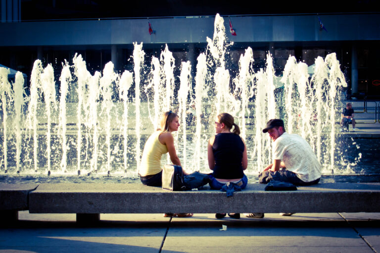 Three people talking by a fountain